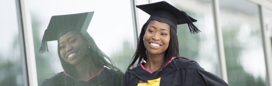 Student with long hair, wearing a graduation cap and gown